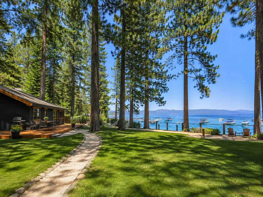 A lakeside cabin surrounded by trees with a path leading to the water.